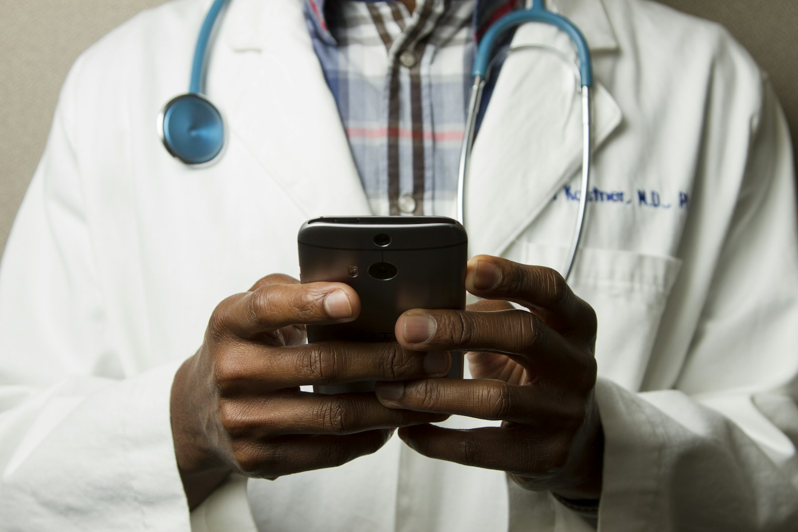 Doctor holding a phone in a white coat with a stethoscope